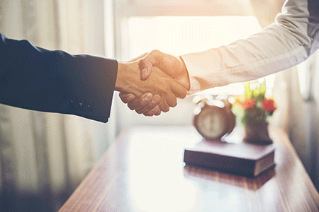 Traders shaking hands after graduating from their trading course.