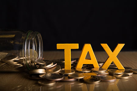 the words tax sitting on a bunch of coins