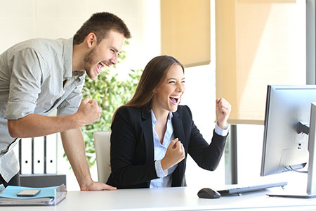 A man and women standing in front of a PC after placing a winning trade