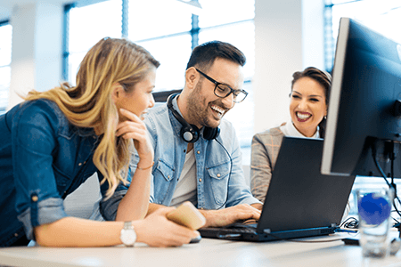 People smiling in front of a computer