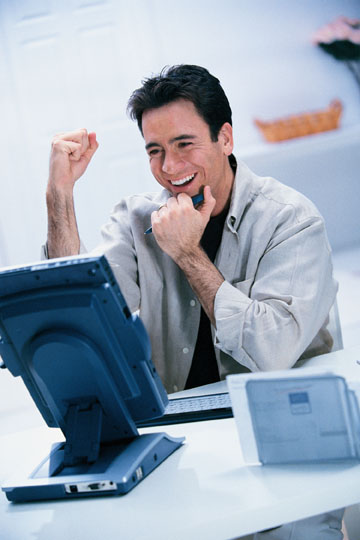 trader in front of a PC with his fist in the air trading to win